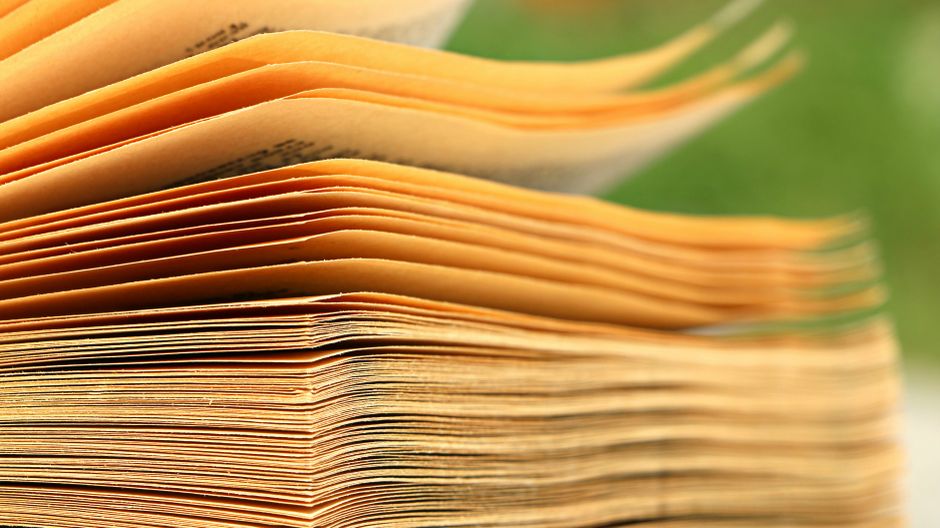 An open vintage book displayed on a wooden surface with dramatic lighting emphasizing its textured pages.