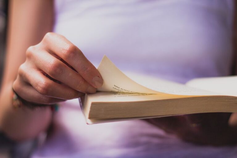 Hand turning a book page, capturing an intimate moment of reading.