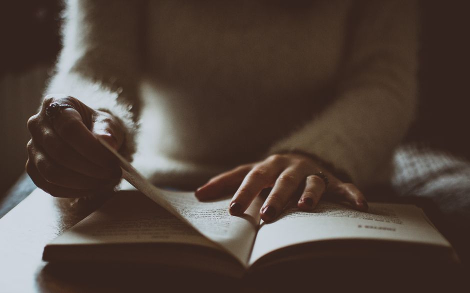 Woman enjoying relaxation by reading a book on a cozy couch indoors.