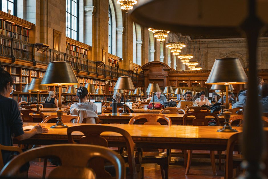 A diverse group of students studying together at a university library, engaged in discussion.